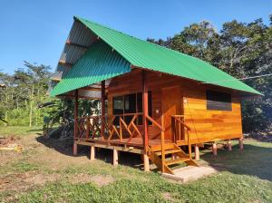 ein kleines Holzgebäude mit grünem Dach in der Unterkunft Quirquincho House in Puerto Maldonado