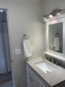 a white bathroom with a sink and a mirror at The Pioneer Studio at 1400K in Anchorage