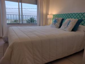 1 cama blanca grande en un dormitorio con ventana en Punta Mar en Mar del Plata