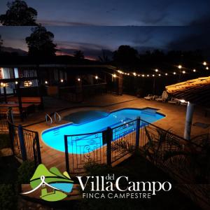 a swimming pool at night with the villa campo fiesta campo logo at Finca Campestre Villa del Campo in Santa Rosa de Cabal