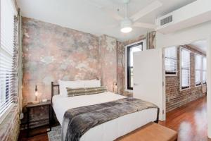a bedroom with a white bed and a brick wall at Modern Apartment in Historic Shell in Memphis
