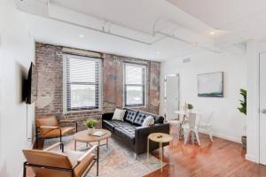 a living room with a black couch and a brick wall at Right on Main St with Historic Vibe! in Memphis