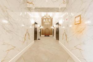 a hallway with white marble walls and a chandelier at The Sutton Place Hotel Halifax in Halifax