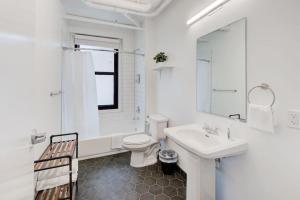 a white bathroom with a toilet and a sink at New Downtown Loft Style Apartment Above Restaurant in Memphis +24 photos