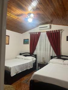 a bedroom with two beds and a wooden ceiling at EL ANHELO in Cumaral
