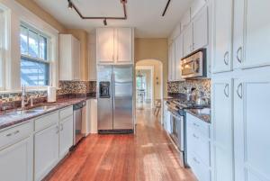a kitchen with white cabinets and a stainless steel refrigerator at Beautiful Bungalow Stones throw from Cooper Young in Memphis