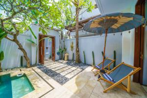 een patio met een stoel, een parasol en een zwembad bij Anema Villa Seminyak in Legian