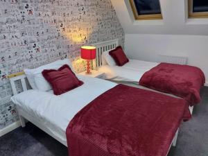 斯溫頓的住宿－Luxury 4 bed house in Swindon，卧室内的两张床和红色枕头