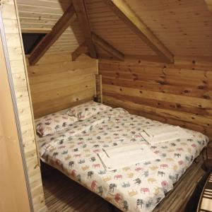 uma cama num quarto com paredes de madeira em Villa FORESTA em Banja Luka