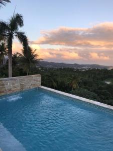 a swimming pool with a sunset in the background at Swim & Paint Art Retreat in Las Piedras