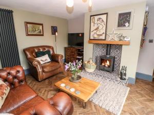 a living room with leather furniture and a fireplace at Pepper Cottage in Bishop Auckland