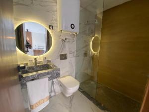 a bathroom with a toilet and a sink and a mirror at Modern 1 BR, 1min from Downtown Anoual Tramway in Casablanca