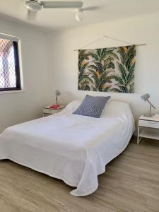 a bedroom with a large white bed with a painting on the wall at 18 Knudsen Street in Elliott Heads