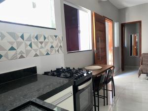 une cuisine avec une cuisinière et un comptoir dans l'établissement Hospedagem dos Massa- Casas no Centro de Arraial- Faça tudo a Pé!, à Arraial do Cabo