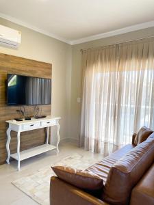 uma sala de estar com um sofá e uma televisão em Residencial Casa Flora - Centro de Bombinhas SC em Bombinhas