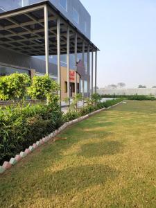 a building with a grass field in front of it at Bellazio Suites Hotel & Resort in Bareilly