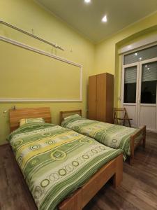 two beds in a room with yellow walls at Apartment Kiki in Novi Sad