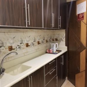 a kitchen with a sink and wooden cabinets at Makkah Jewel Hotel in Makkah