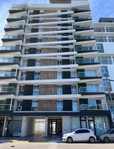 プエルト・マドリンにあるDepartamento Caleta Viewの前に車が駐車されている大きな建物