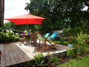 uma mesa e cadeiras sob um guarda-sol num deque de madeira em Charming holiday home with garden em Huelgoat