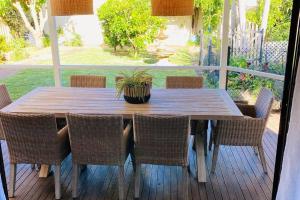 a wooden table with chairs and a potted plant on a porch at 'Wishing Well' - Beautiful 4 bed, 2 bath house at Shoal Bay Beach in Shoal Bay