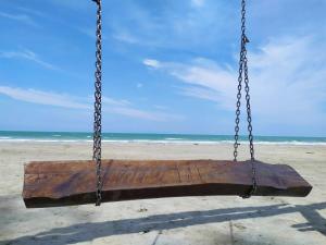 a swing on the beach with the ocean in the background at JoJo Homestay Tiara Residence in Desaru