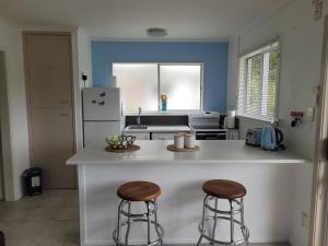 een keuken met 2 barkrukken en een aanrecht bij He pai te Wairua by the Sea in Paihia
