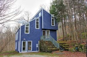 ein blaues Haus mit Treppen im Wald in der Unterkunft Rustic 3 bedroom home Moose Lodge in Killington