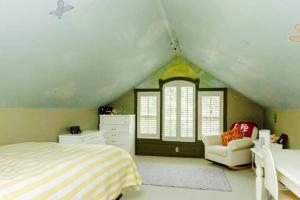 ein Schlafzimmer mit einem Bett und einem Stuhl im Dachgeschoss in der Unterkunft Luxury Vacation Estate in Pottstown