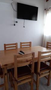 mesa de madera con sillas y TV en la pared en Casa Villa Zorzal en Villa Larca