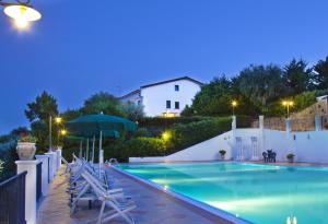 a swimming pool at night with chairs and a building at Residence Chiesiola in Vieste