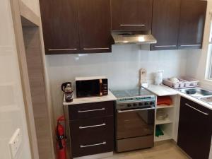 a small kitchen with a stove and a microwave at 2 Bedroom Duplex House - 3 Bathrooms, Balcony , Kitchen, Living Room, - 24 7 Security, Gated, Gym, Pool, Wifi, DSTV, in Tema