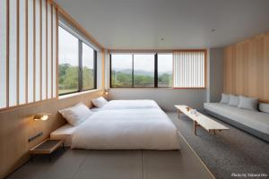 a bedroom with a bed and a couch and windows at MIROKU NARA by THE SHARE HOTELS in Nara