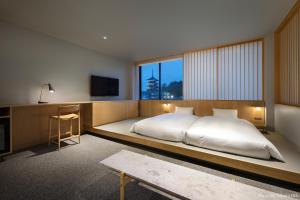 奈良MIROKU 奈良酒店-共享酒店(MIROKU NARA by THE SHARE HOTELS) 的一间卧室配有一张床、一张书桌和一台电视。 更多37张照片