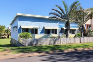 une maison bleue avec une clôture et un palmier dans l'établissement 115 Esplanade, à Bargara