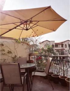 un tavolo e sedie con ombrellone su un balcone di Semenyih Escapar Villa by Dan a Semenyih