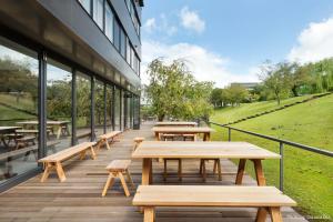 奈良MIROKU 奈良酒店-共享酒店(MIROKU NARA by THE SHARE HOTELS) 的大楼外的自助餐厅,设有木桌和长椅