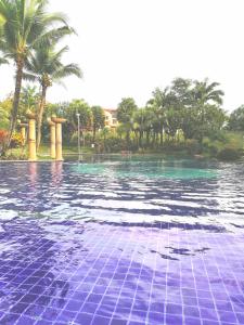 een zwembad met blauwe tegels voor de palmbomen bij Semenyih Escapar Villa by Dan in Semenyih