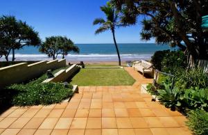 a walkway to the beach with benches and the ocean at Beach at your feet in Bargara