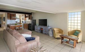 a living room with two couches and a kitchen at Beach at your feet in Bargara