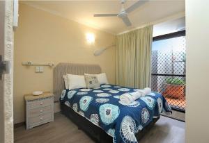 a bedroom with a blue and white bed and a window at Beach at your feet in Bargara