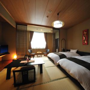 1 dormitorio grande con 2 camas y TV en Watari Onsen Bettei-Kaede, en Hanamaki