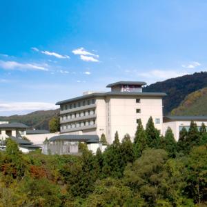 un gran edificio blanco en medio de árboles en Watari Onsen Bettei-Kaede, en Hanamaki