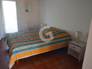 un letto con piumone a righe in una camera da letto di Maison La Tranche-sur-Mer, 4 pièces, 6 personnes - FR-1-357-44 a La Tranche-sur-Mer