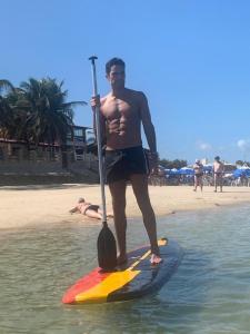 a man standing on a paddle board on the beach at Sonia Flats Arituba Tropical - Flat vista mar em frente à Praia de Camurupim in Nísia Floresta