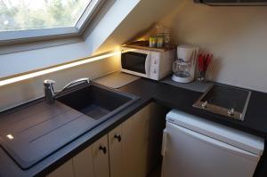 a kitchen with a sink and a microwave at 't Valkennestje in De Haan