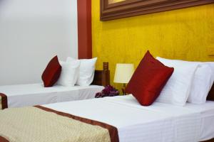 two beds with red pillows in a hotel room at Meili Lanka City Hotel in Kandy