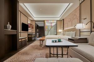 a hotel room with a bed and a couch and a table at Shangri-La Qiantan, Shanghai in Shanghai