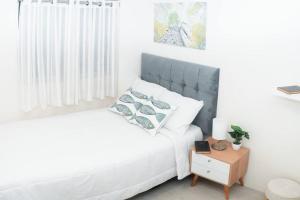 a white bedroom with a bed and a night stand at Hermoso departamento de estreno in Lima