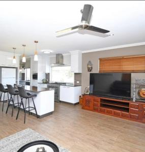 a large kitchen and living room with a flat screen tv at Two Storey Beach House in Hervey Bay
